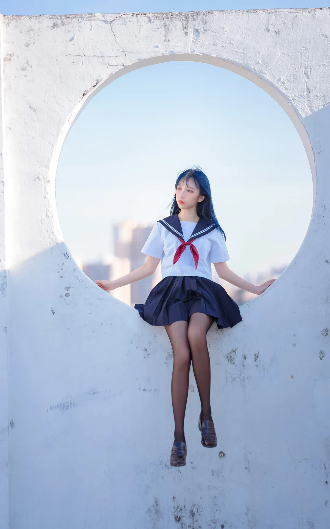 果咩酱w穿着学生制服坐在圆形结构上，背景是蓝天