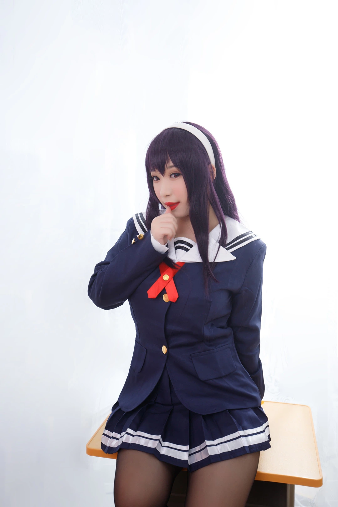 纯白背景中坐在课桌边的深色制服人物，手指轻触嘴唇姿态柔和