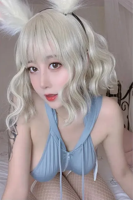 奈汐酱nice扮演蓝色兔女郎角色,佩戴白色兔耳,低胸紧身蓝色服装,半俯身近拍镜头