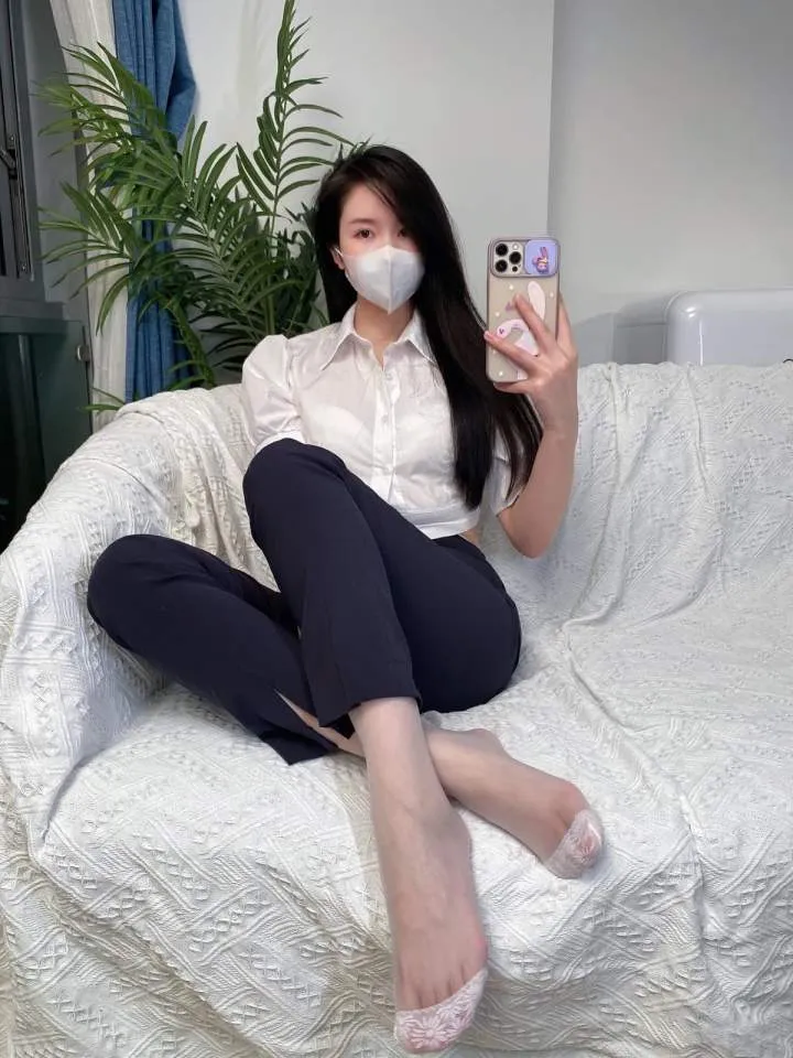 白色沙发前白衬衣黑裤与长发口罩自拍坐姿图
