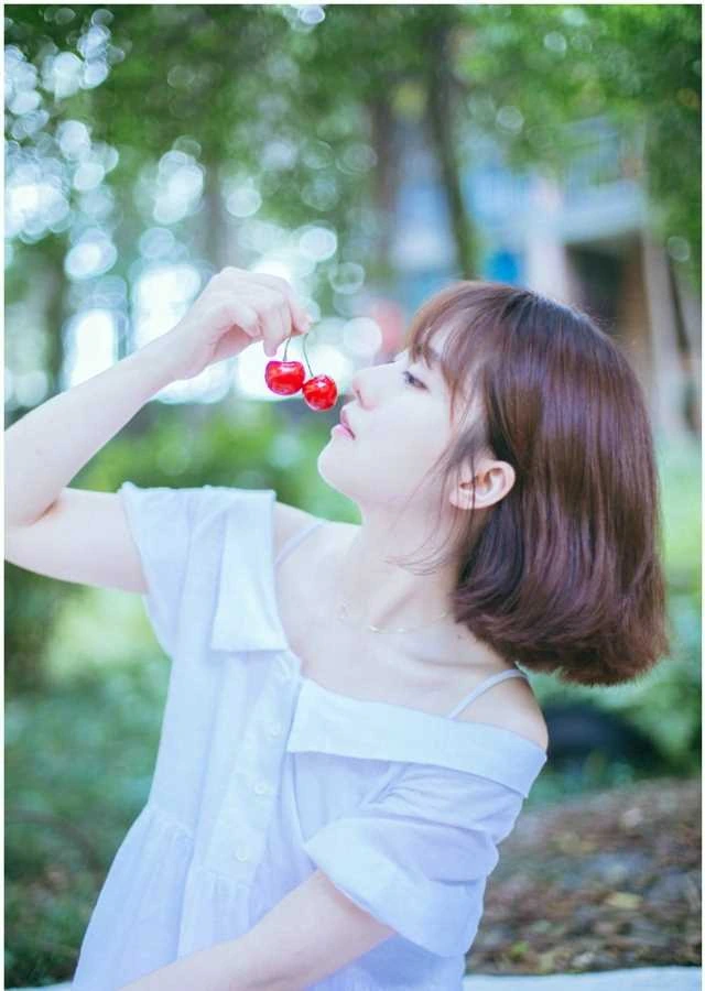 爱丽莎在树荫光斑背景下侧身举手出镜,白色上衣与短发造型细节清晰
