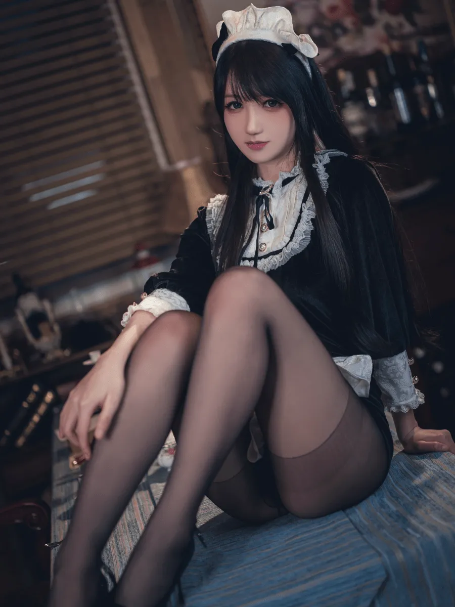 抖个姬灵穿黑白女仆装坐在室内，头饰和黑色丝袜形成完整造型
