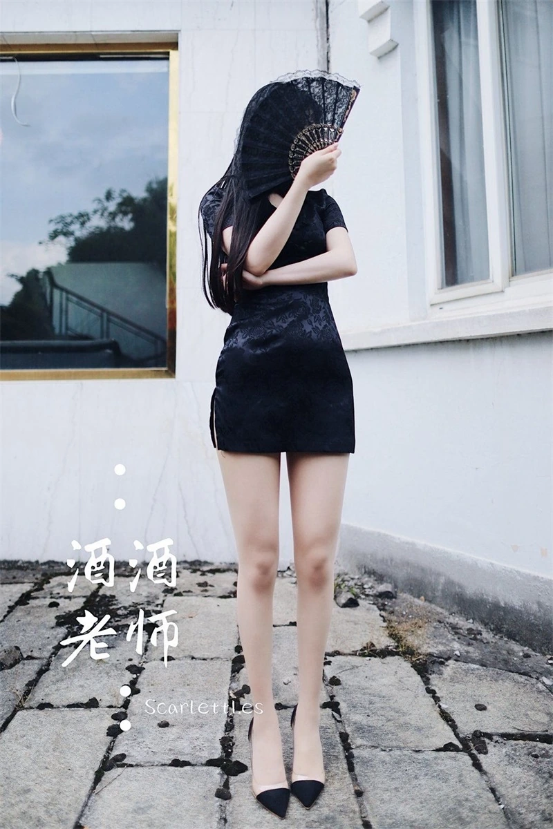 酒酒老师在室外屋顶通道站姿出镜并手持折扇，黑色短旗袍与高跟鞋细节清晰