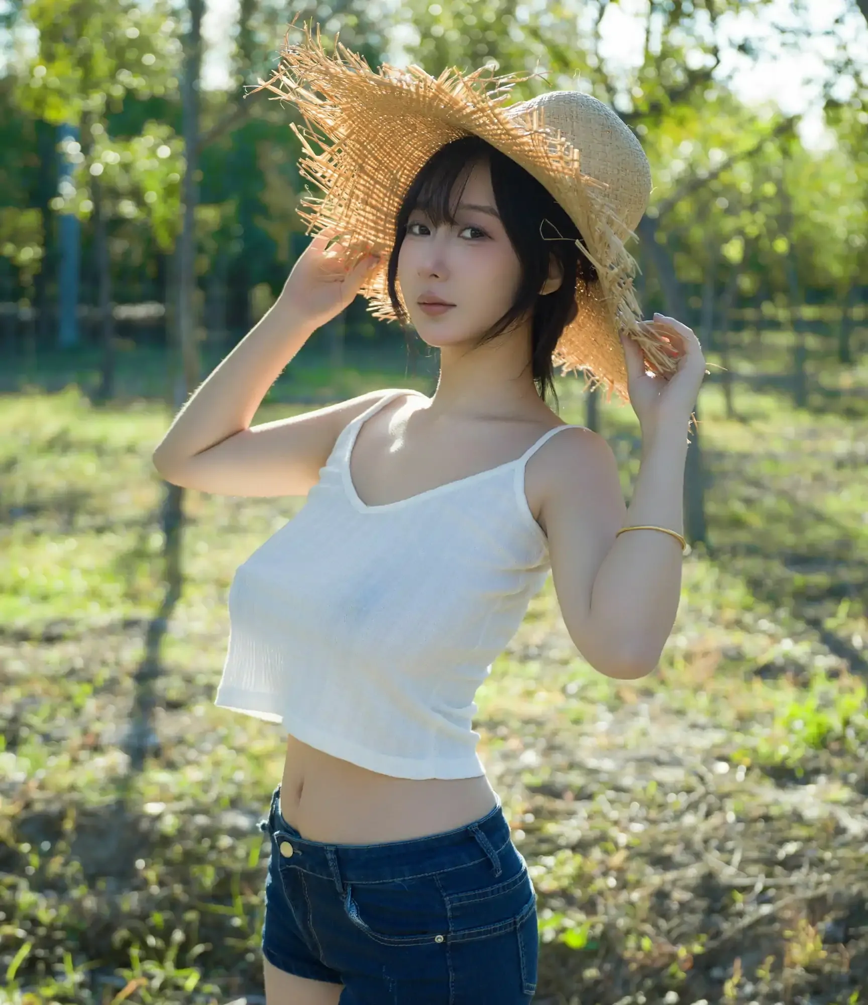 浅安安Yuki站在户外阳光下扶着草帽,穿白色背心和牛仔短裤的自然造型