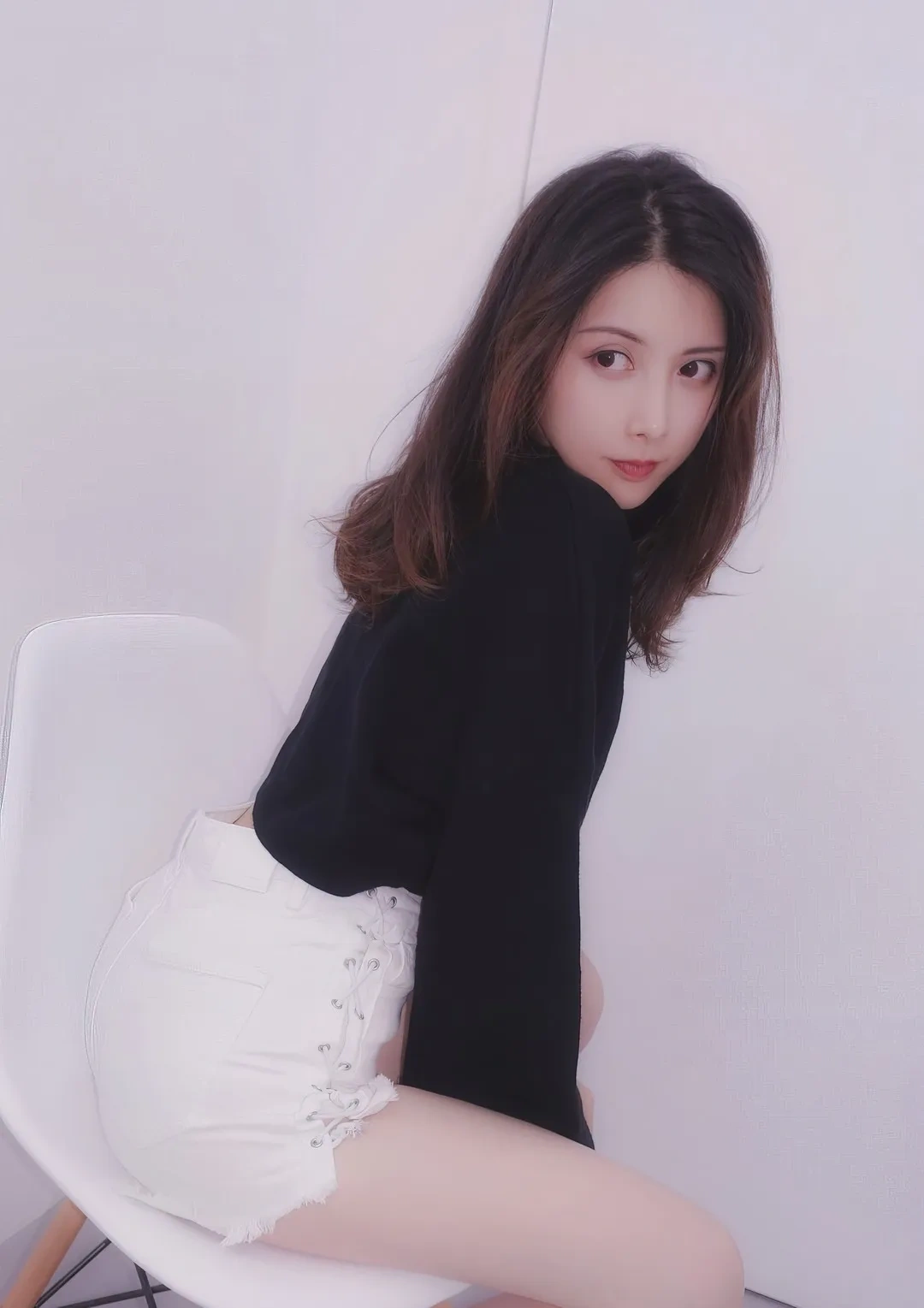 摄影师mix作品中长发模特坐在白色沙发上,穿黑色上衣和白色短裙 写真