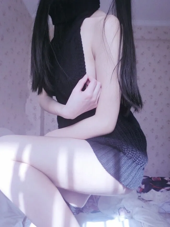 双马尾少女赛高酱侧坐在床边穿黑色针织裙的近景照片