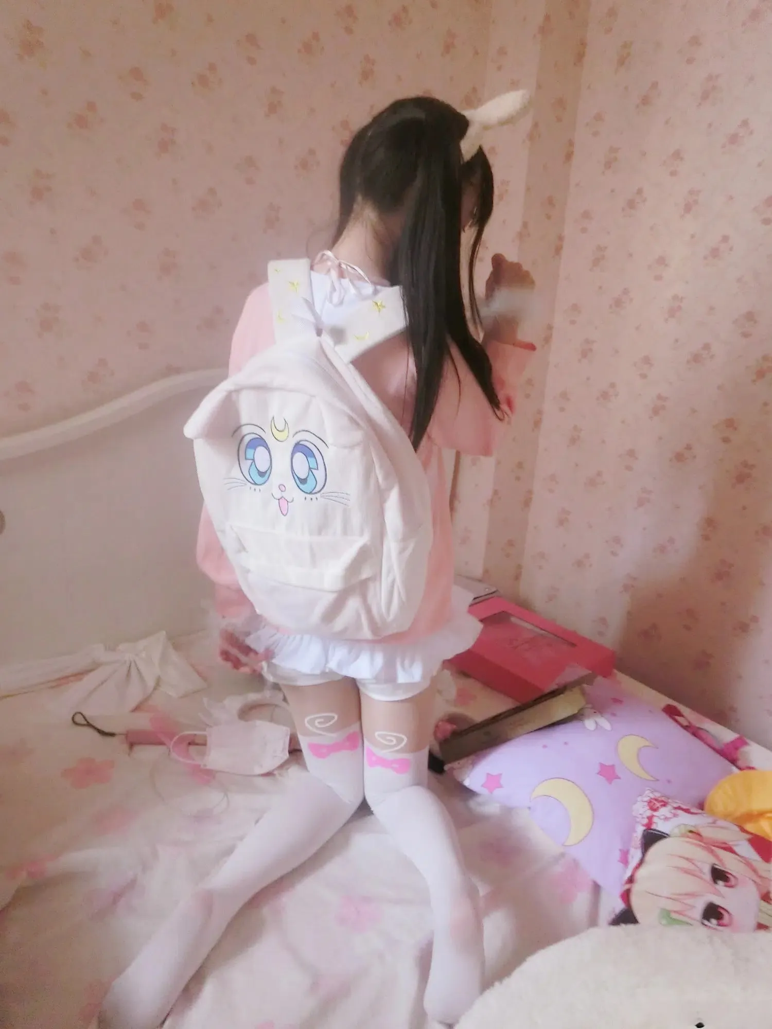 双马尾少女赛高酱坐在床上背对镜头背着白色双肩包的照片