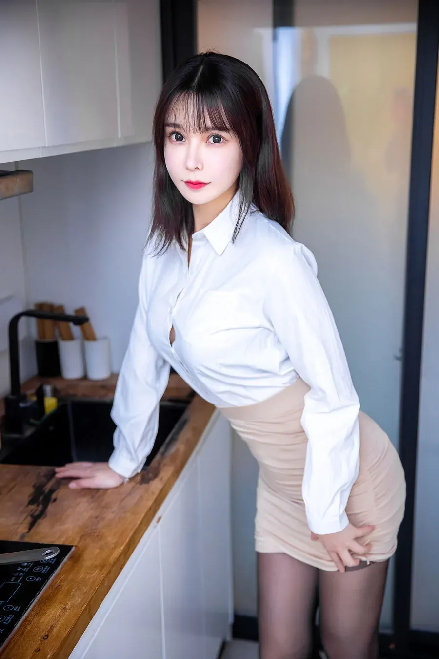 亚马逊鲶鱼穿白衬衫和米色短裙倚靠木质吧台的写真