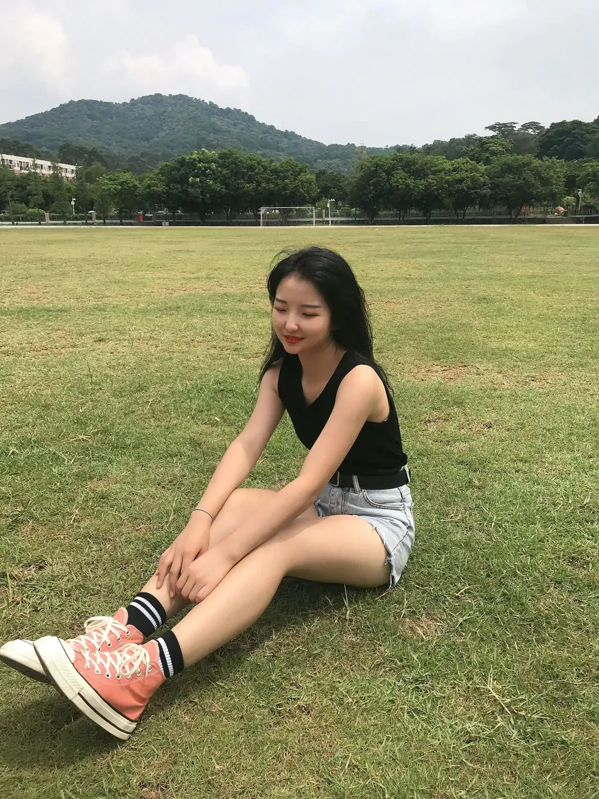最爱帆布鞋穿黑色背心和牛仔短裤坐在草地上的写真