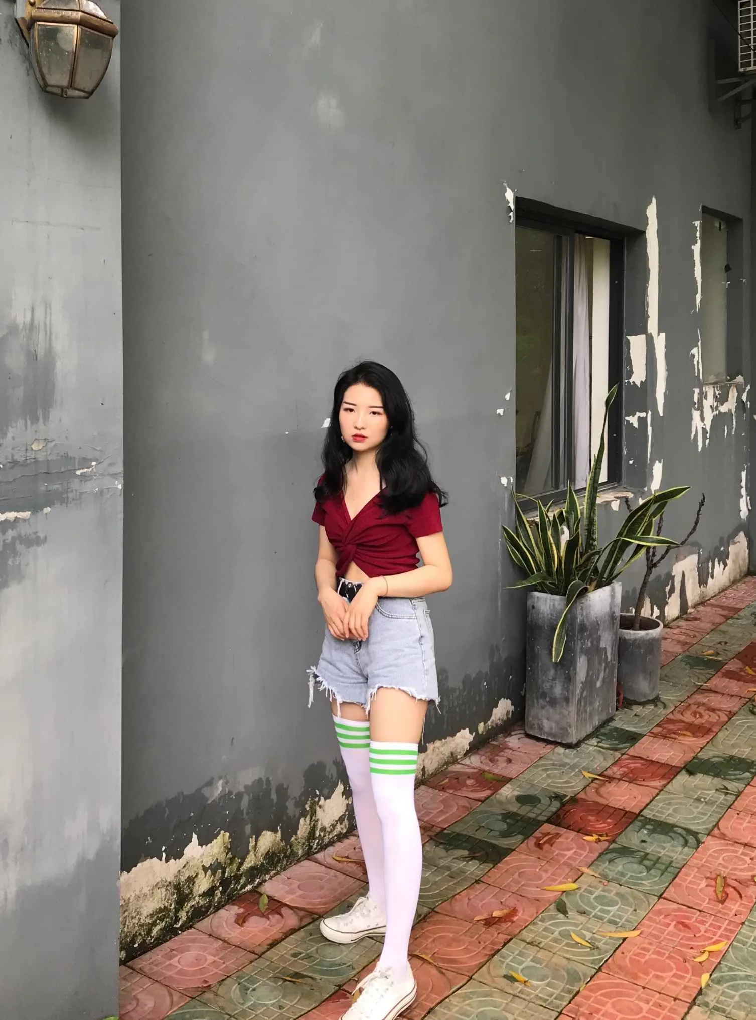 最爱帆布鞋穿红色上衣和牛仔短裤站在灰墙旁的写真