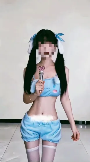 苏小柠蓝色兔耳头饰和浅蓝服饰手持道具站在白墙前