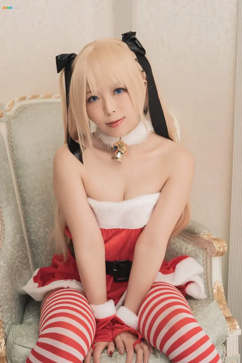 Rizuna 金色长发穿红白圣诞风服装坐在浅色椅子上的 cosplay 画面