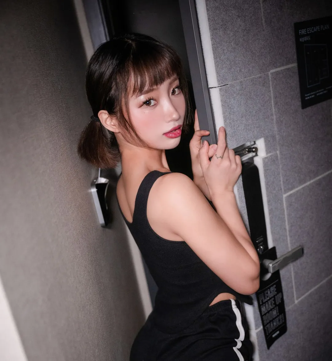 BootyQueen 低双马尾黑色无袖上衣站在灰色门边空间