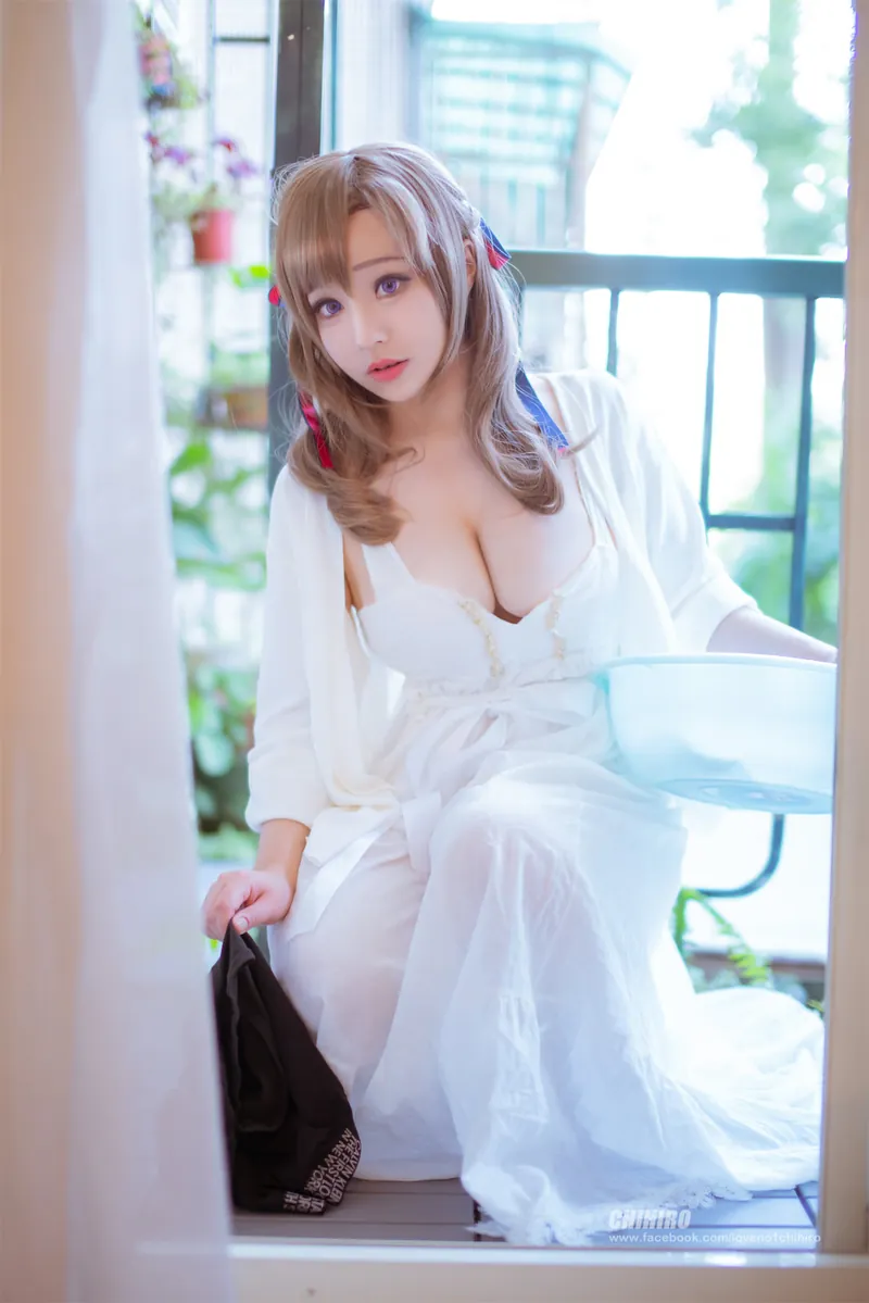 Joyce 浅棕双马尾白色服饰窗边坐姿写真,背景有阳台栏杆和室内绿植