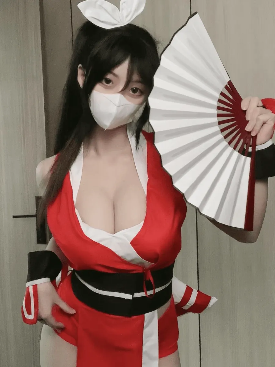 突变的柠檬红白服饰造型,佩戴白色口罩和白色头饰,手持白色折扇站在室内背景前