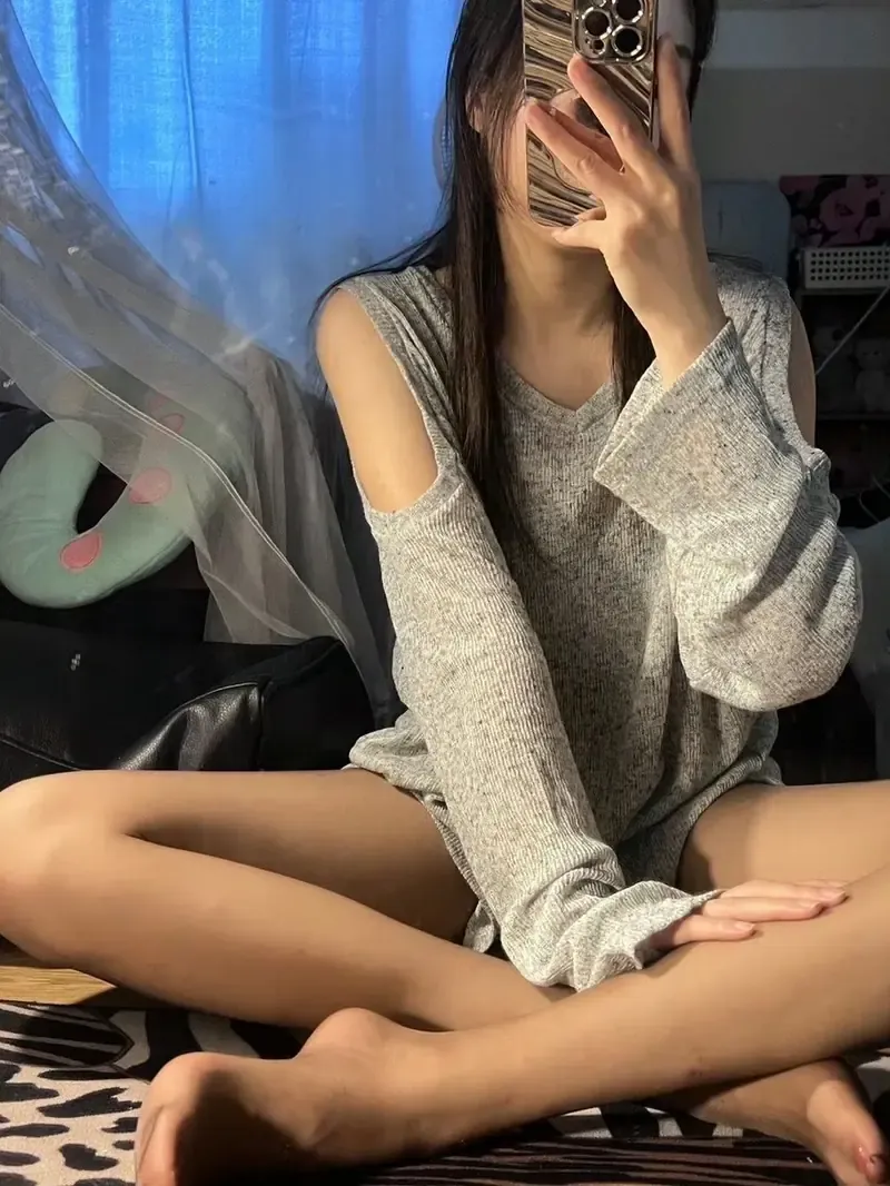 ELaine小仙女穿灰色露肩针织衫盘腿坐在室内用手机遮脸自拍