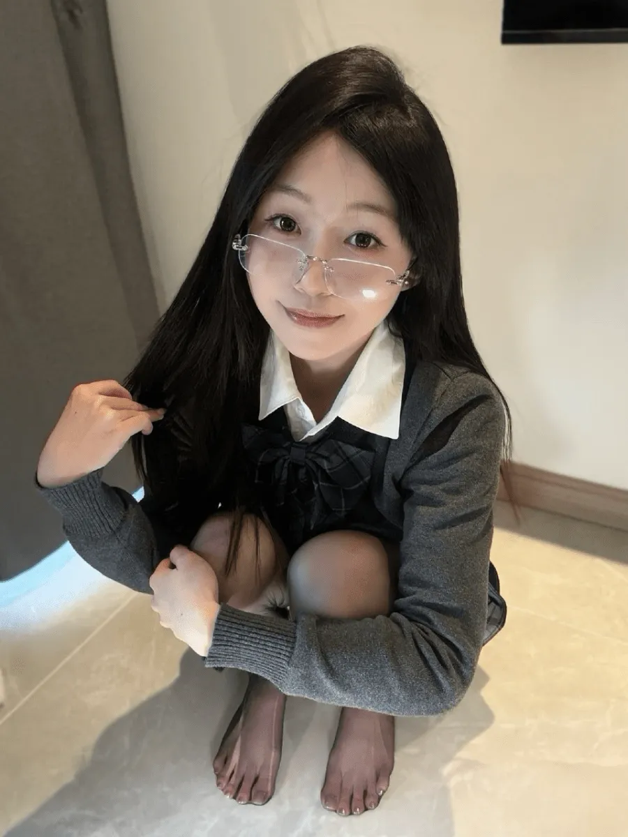 抖音别拔虎牙黑色长发戴透明眼镜,穿灰色开衫和白衬衫蹲坐自拍