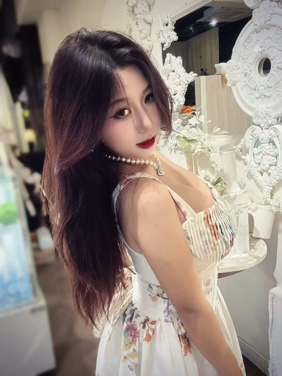 抖音小云同学深色长发穿白色花纹连衣裙，站在白色装饰镜旁