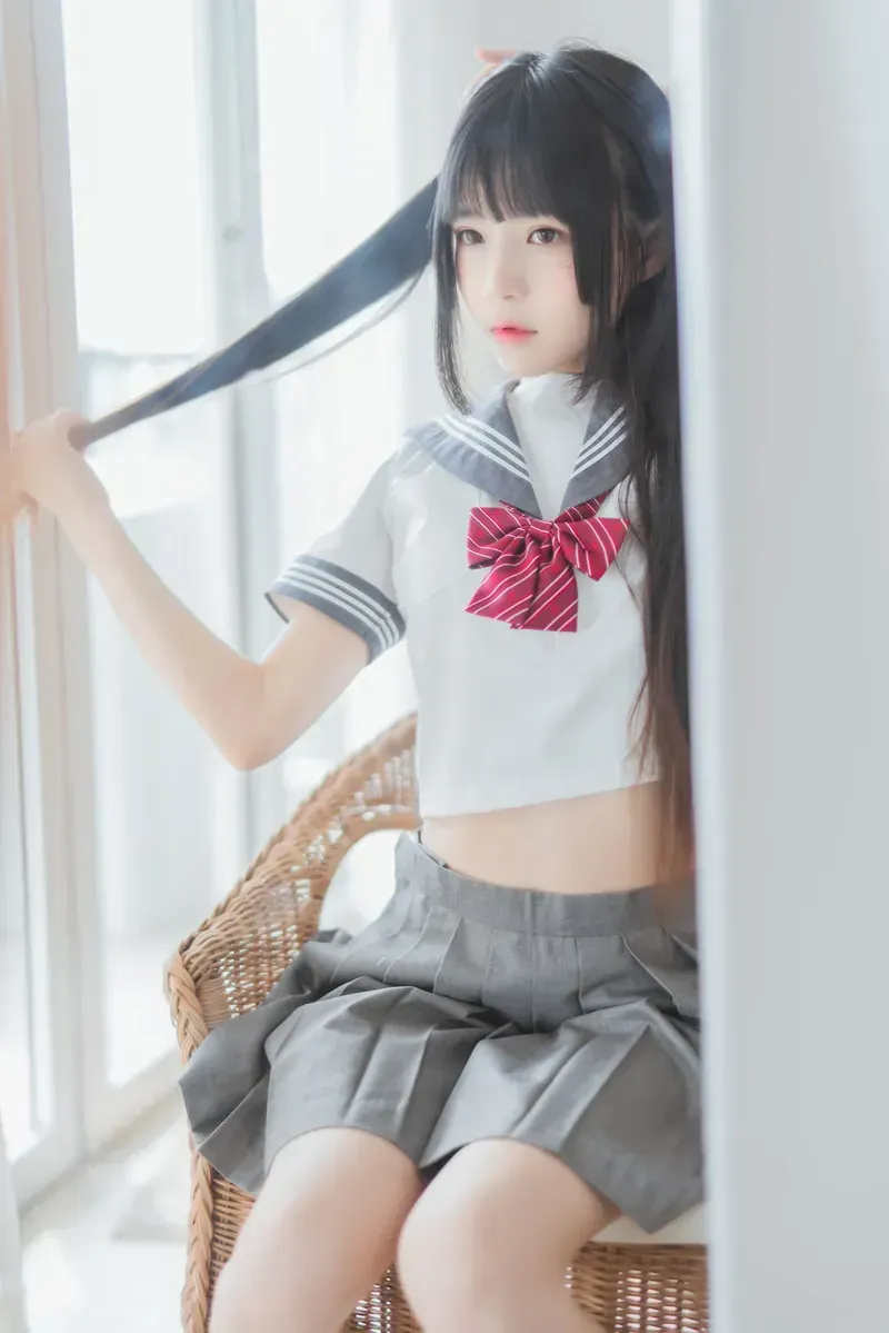 鹿八岁baby穿白色水手服和灰色百褶裙坐在窗边藤椅上