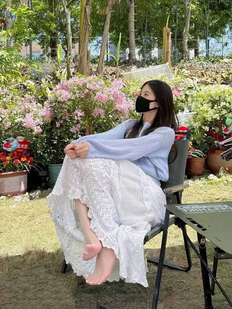 抖音小步里穿白色针织上衣和白色长裙坐在花园椅上的户外写真