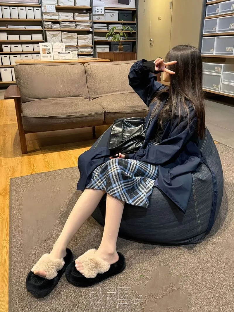 抖音小步里穿深色外套和格纹裙坐在室内懒人沙发上的写真